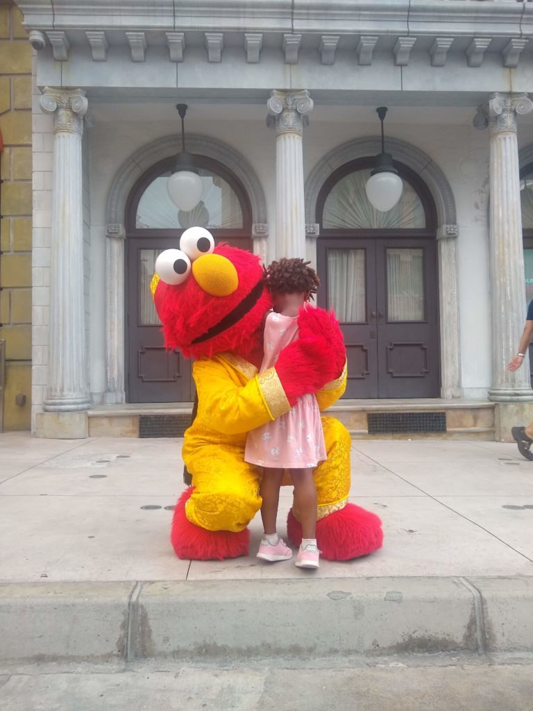 Little girl hugging Elmo.